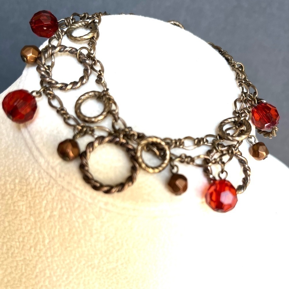 Antiqued brass finish two strand circle red/copper faceted bead charm bracelet.